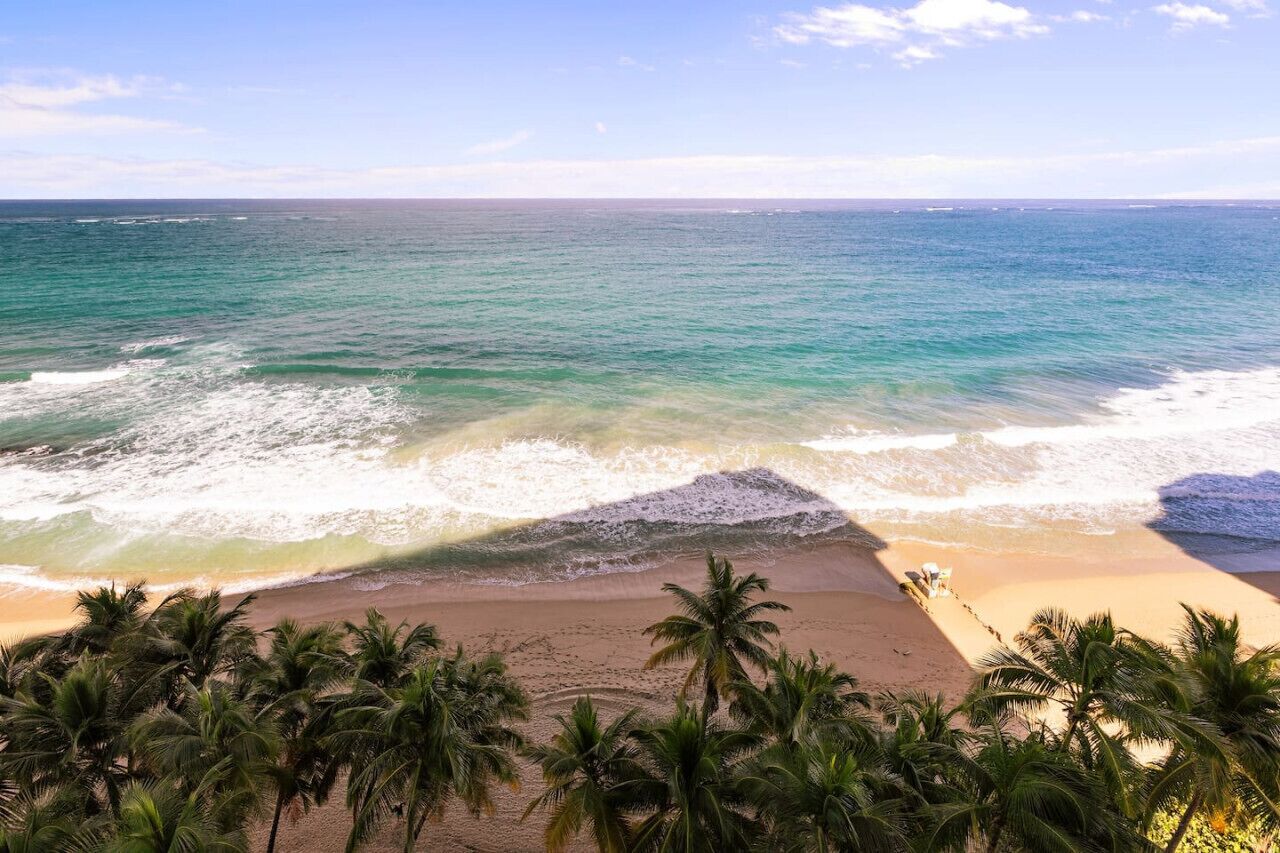 Ein Strand mit klarem türkisblauem Wasser, Palmen und einem Sandstrand.