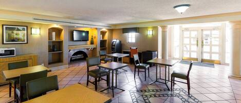 A hotel room with a dining area, a fireplace, a television, and a large window.