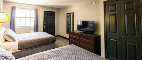 Une chambre d’hôtel avec deux lits, une télévision, une commode et une porte.