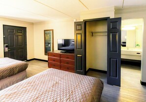 A hotel room with two beds, a dresser, a television, and a mirror. - Home Suites Culebra (San Antonio)