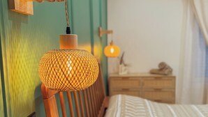 Une chambre à coucher avec une tête de lit en bois, une lampe à motifs et un lit recouvert d’une couvre-lit à chevrons.