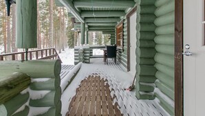 A log cabin with a wooden deck and a covered porch.