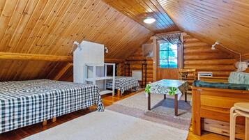 A cozy attic bedroom with two beds, a desk, and a window.