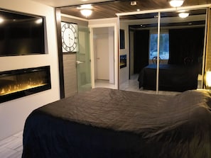 Makuuhuoneessa on sänky, takka, kello ja ikkunasta avautuva näkymä lumiseen maisemaan.