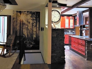 A modern kitchen with red cabinets, a stone accent wall, and a large clock. - Villa meka by Interhome (Sastamala)