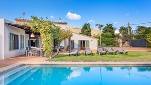 Ein Poolbereich mit Pool, Sitzgelegenheiten im Freien und einem Haus mit Pergola.