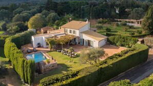 Eine Villa mit Swimmingpool, umgeben von gepflegten Gärten und Blick auf einen Berg.