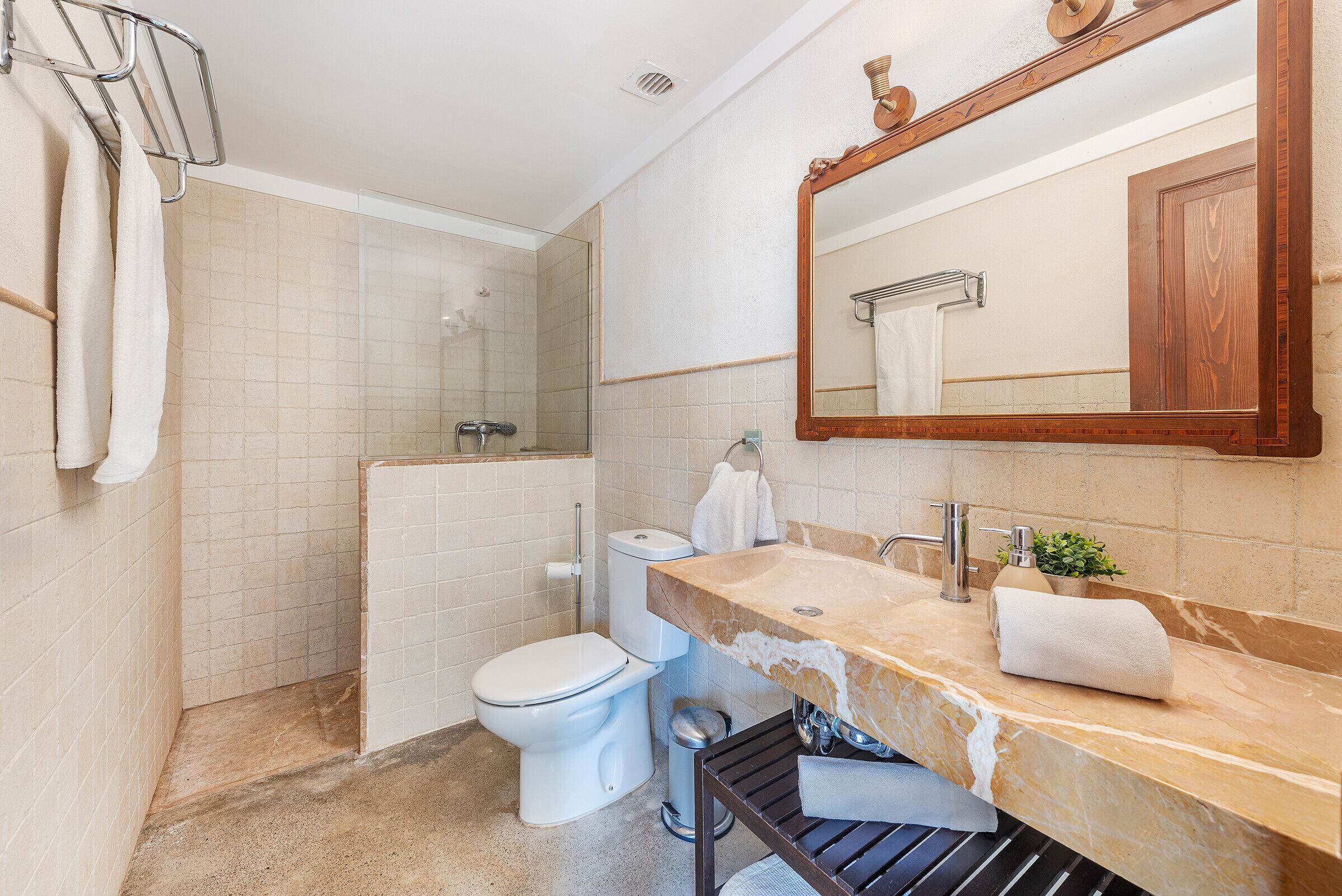 A bathroom with a toilet, sink, mirror, and towel rack.