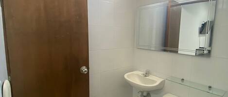A small, clean bathroom with a toilet, sink, and mirror.