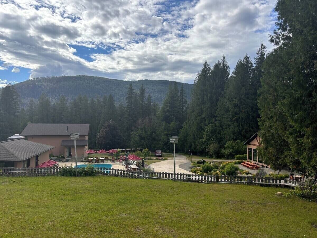 A resort with a swimming pool, outdoor seating, and a mountain backdrop.