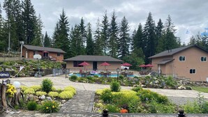 Een zwembad met ligbedden en parasols, omgeven door een aangelegde tuin met verschillende planten en bloemen.