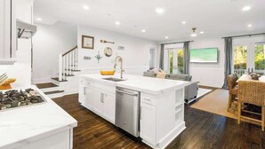 A modern kitchen with white cabinetry, a central island with a sink, and a dining area with a table and chairs.
