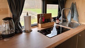 Eine kleine Küche mit eingebautem Herd, Spüle und einem Fenster mit Vorhängen.