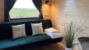 Ein gemütliches Zimmer mit einem grünen Sofa, einer Topfpflanze und einem Fenster mit Vorhängen.