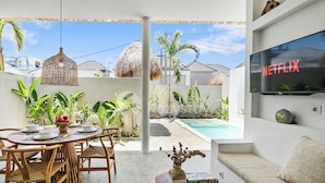 A modern outdoor dining area with a pool, a TV displaying 'NETFLIX', and a cozy seating area. - Kalea Villa by Kozystay - Ungasan (Ungasan)