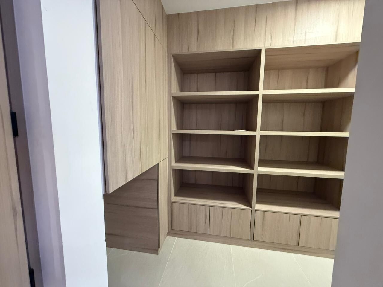 A modern, multi-shelved wooden storage unit with a minimalist design, likely used for organizing personal items.