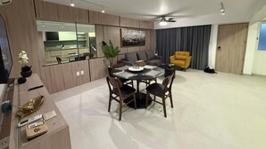 Ein modernes Wohnzimmer mit Essbereich, einer Couch, einem gelben Sessel und einem großen Spiegel.
