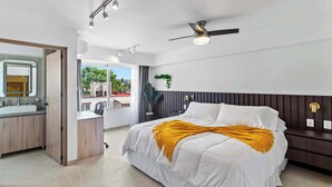 Une chambre à coucher moderne avec un lit, une table de chevet et un ventilateur de plafond.