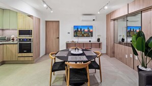 Une cuisine moderne dotée d’appareils électroménagers intégrés, un coin repas avec une table ronde et des chaises, et un tableau représentant un paysage urbain accroché au mur.