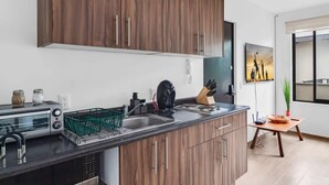 A modern kitchen with wooden cabinets, a built-in oven, and a sink. - Ms Magnifica Suite Ubicadisima (Santiago de Querétaro)