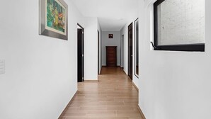 A narrow hallway with wooden flooring, white walls, and a framed painting on the left. - Ms Magnifica Suite Ubicadisima (Santiago de Querétaro)