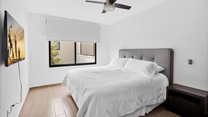 A bedroom with a bed, a ceiling fan, a window with a view, and a wall-mounted TV. - Ms Magnifica Suite Ubicadisima (Santiago de Querétaro)