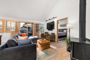 Een moderne woonkamer met een bank, fauteuils, een open haard en een televisie.