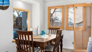 A dining area with a wooden table and chairs, a clock on the wall, and wooden blinds on the windows. - Relaxing Getaway Overlooking Schwan Lagoon (Santa Cruz)