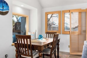 A dining area with a wooden table and chairs, a clock on the wall, and wooden blinds on the windows. - Relaxing Getaway Overlooking Schwan Lagoon (Santa Cruz)