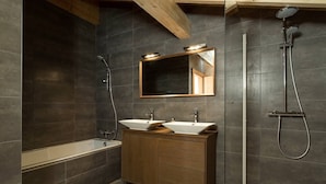Un baño moderno con tocador de madera, un espejo grande, una bañera y una ducha.