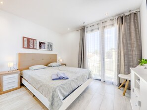 Relax in a serene space with a large bed, desk, and potted plant, surrounded by abstract artwork.
