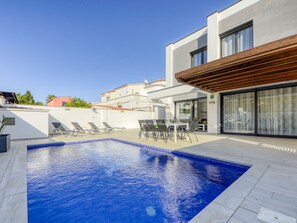 Relax by the rectangular pool surrounded by lounge chairs and a wooden pergola.