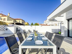 Enjoy meals al fresco at this outdoor dining area, surrounded by a swimming pool and offering views of the neighborhood.