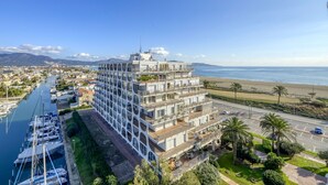Un hôtel à plusieurs étages doté de balcons donnant sur une marina et une plage.