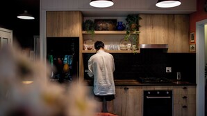 Moderni keittiö, jossa on puiset kaapit, liesi ja riippuvalaisimet.