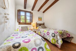 Une chambre avec deux lits, une fenêtre, une lampe et un tableau au mur.