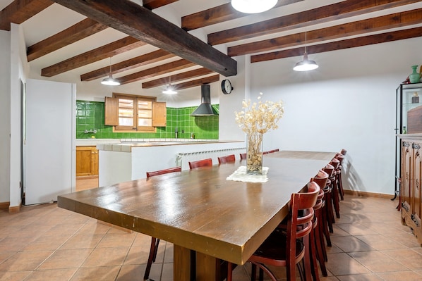 Une cuisine avec des poutres en bois, une grande table à manger et des chaises rouges.