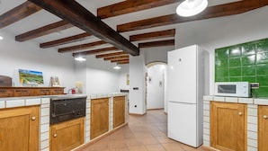 Une cuisine avec des meubles en bois, un réfrigérateur blanc, un four à micro-ondes et un crédence recouverte de carreaux verts.