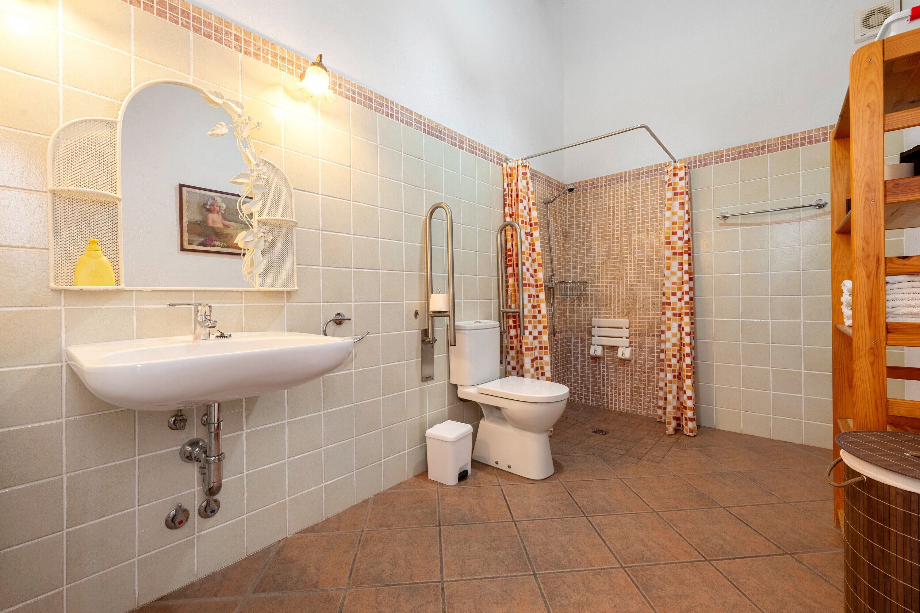A bathroom with a sink, toilet, shower, and a wooden shelf.
