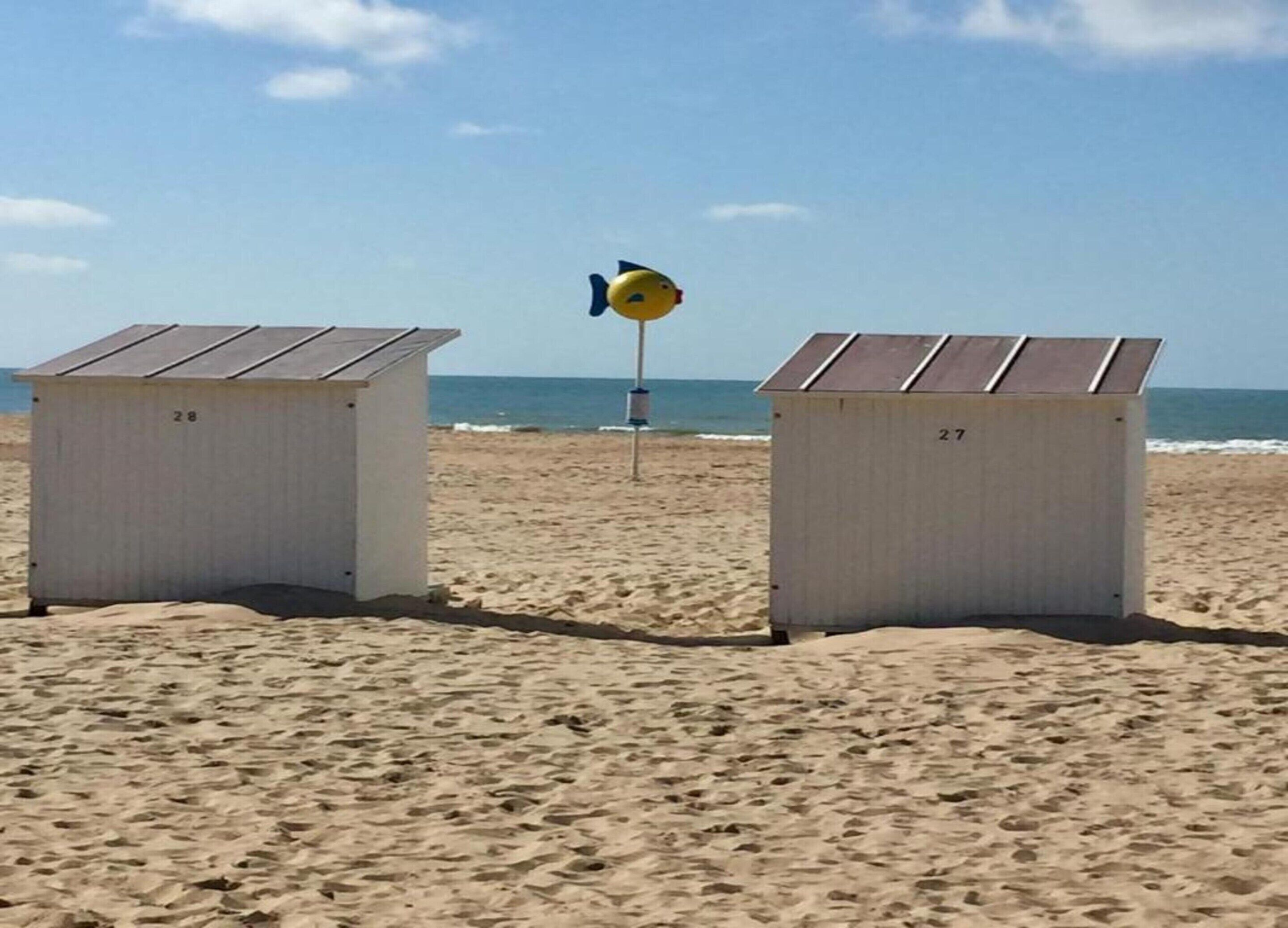 Two beach huts numbered 28 and 27 with a lifeguard tower in the background.