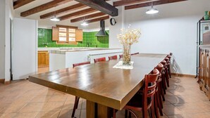 Una cocina con vigas de madera, una gran mesa de comedor y sillas rojas.