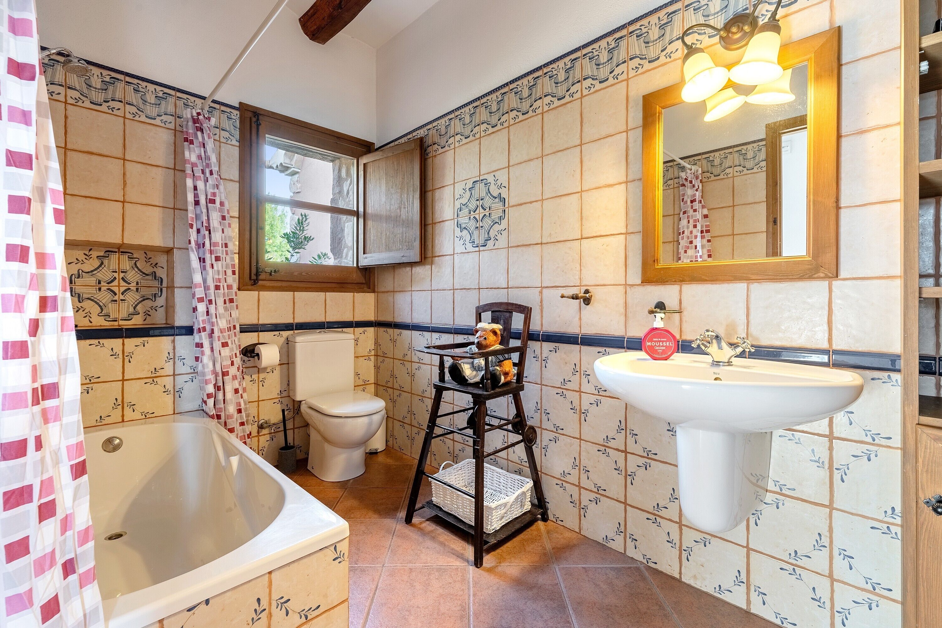 Een badkamer met een bad, toilet, wastafel en spiegel.