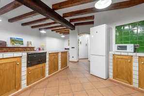 Eine Küche mit Holzausstattung, einem weißen Kühlschrank, einer Mikrowelle und einer grünen Fliesenrückwand.