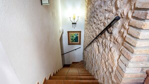 Una escalera con barandilla, un aplique de pared y un cuadro enmarcado.