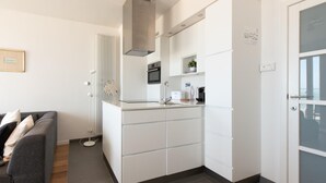Une cuisine moderne avec des meubles blancs, une hotte en acier inoxydable et un four encastré.