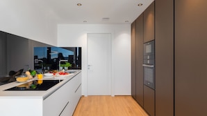 Een moderne keuken met een centraal eiland, inbouwapparatuur en een uitzicht op de stadsgezicht door een groot raam.