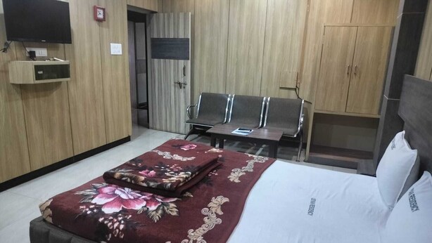 A hotel room with a bed, a desk, a chair, and a wardrobe. - I-ROOMZ Udhyan Residency (Gulbarga)