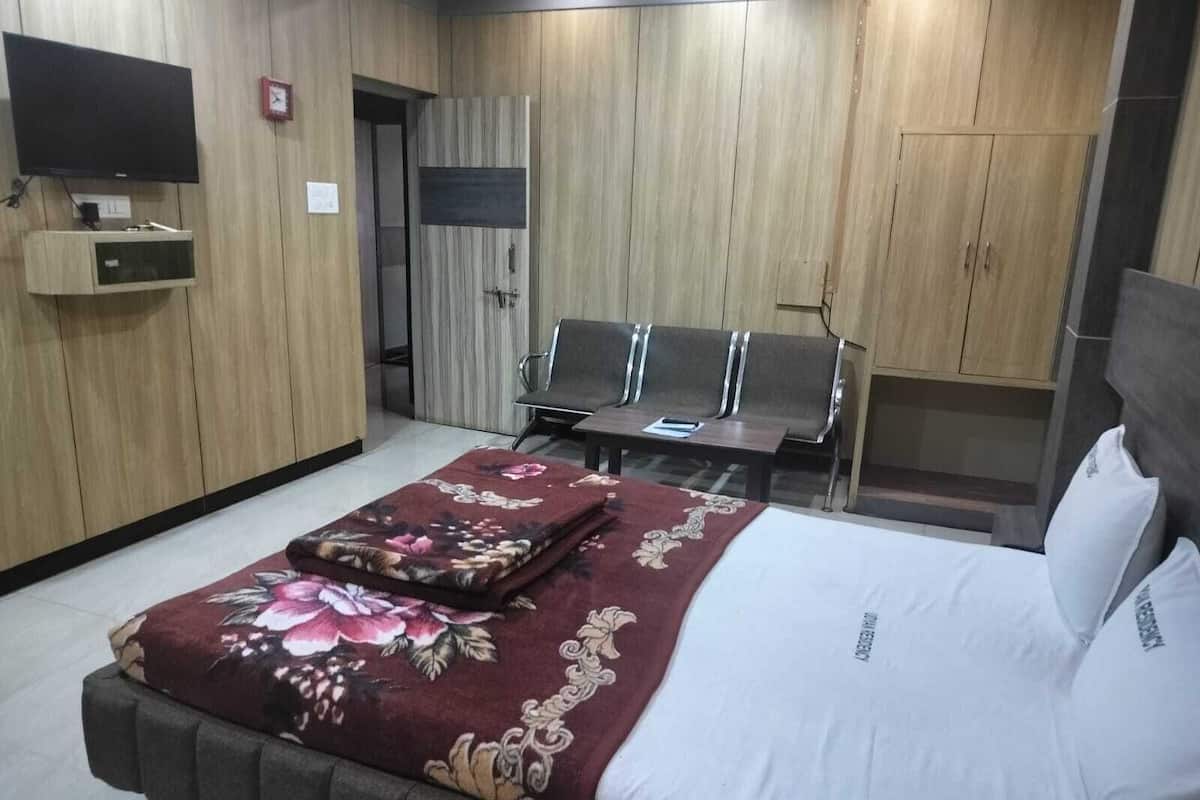 A hotel room with a bed, a desk, a chair, and a wardrobe.