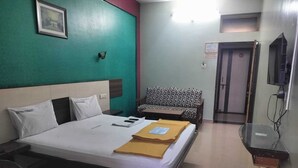A hotel room with a bed, a sofa, a TV, and a small table. - I-ROOMZ Udhyan Residency (Gulbarga)