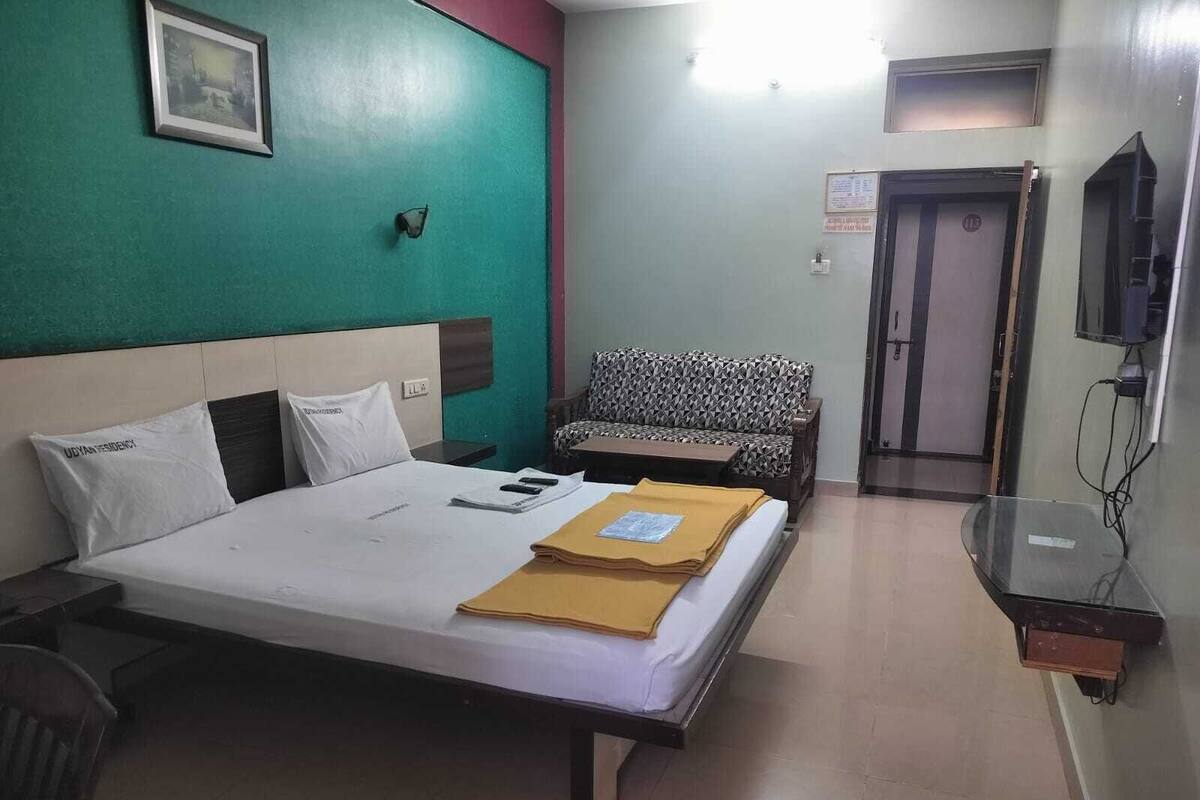 A hotel room with a bed, a sofa, a TV, and a small table.